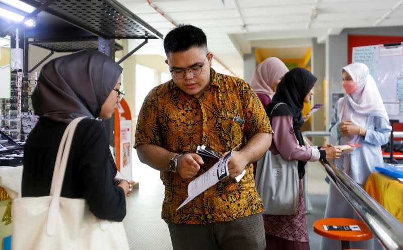 Zaim Mustaqim Marzuki explains to his fellow undergraduate the process of casting a vote for Malaysia's upcoming general election at Gombak