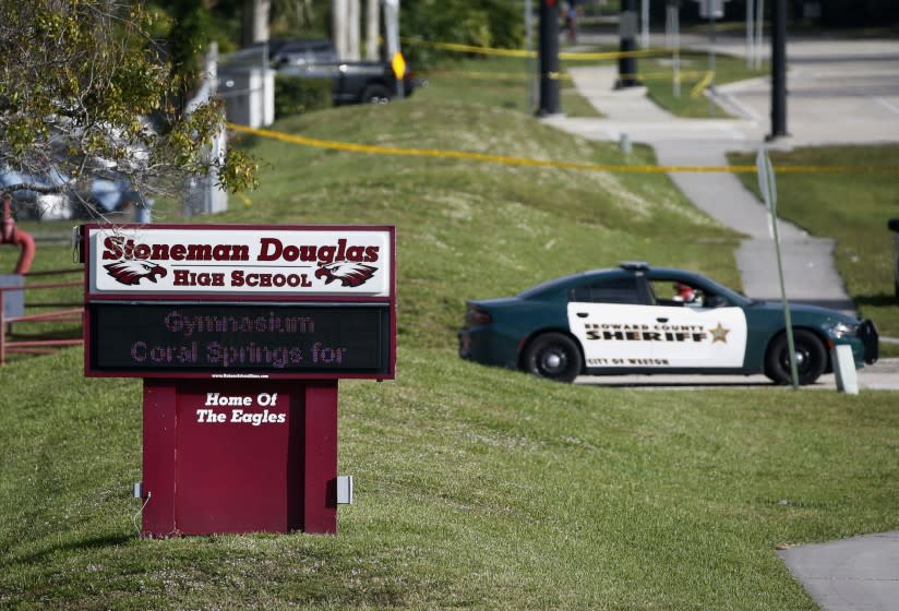 FILE- In this Feb. 15, 2018, file photo, law enforcement officers block off the entrance to Marjory Stoneman Douglas High School in Parkland, Fla., following a deadly shooting at the school. A California man who is on the autism spectrum was sentenced Monday, March 2, 2020, to more than five years in prison for cyberstalking families of Parkland, Florida, school shooting victims. (AP Photo/Wilfredo Lee, File)
