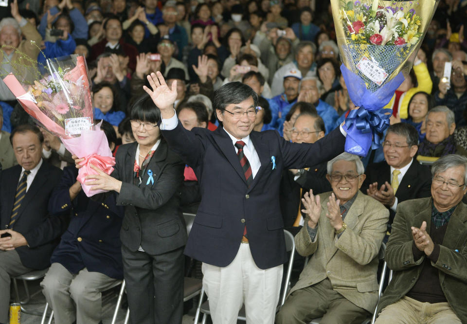 Nago city Mayor Susumu Inamine, center right, and his wife Ritsuko celebrate after he was re-elected in the mayoral election in Nago, on the southern Japanese island of Okinawa, Sunday, Jan. 19, 2014. The election is being closely watched from Washington to Tokyo as a referendum on long-delayed plans to move a U.S. air base to the community of 62,000 people. (AP Photo/Kyodo News) JAPAN OUT, MANDATORY CREDIT