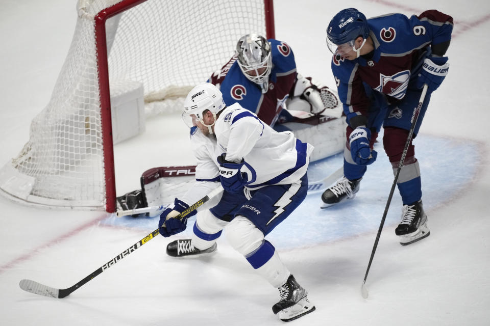 Tampa Bay Lightning center Steven Stamkos, front, directs a shot at Colorado Avalanche goaltender Alexandar Georgiev, back left, as center Evan Rodrigues defends during overtime of an NHL hockey game Tuesday, Feb. 14, 2023, in Denver. (AP Photo/David Zalubowski)
