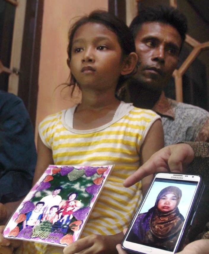 Desi Sri Rahayu, the ten-year-old daughter of Karni Binti Medi Tarsim, an Indonesian domestic worker executed in Saudi Arabia, holds a family potrait as she sits with her father Darpin at their home in Brebes in central Java on April 17, 2015 (AFP Photo/)