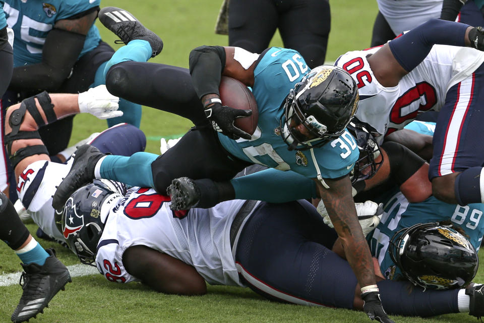 Jacksonville Jaguars running back James Robinson (30) dives over the Houston Texans defensive line for a 1-yard touchdown during the first half of an NFL football game, Sunday, Nov. 8, 2020, in Jacksonville, Fla. (AP Photo/Stephen B. Morton)