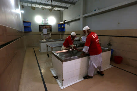 Employees of the Edhi Foundation morgue clean work tables after washing a body at the Edhi morgue in Karachi, Pakistan May 13, 2016. REUTERS/Akhtar Soomro