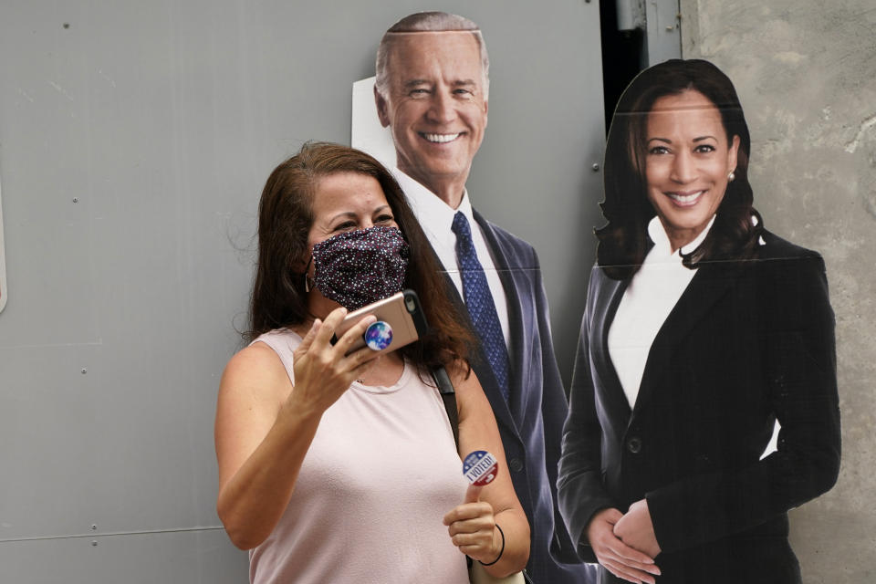 Yaidi Clery, left, holds up an "I Voted" sticker as she stands with a cutout of Democratic presidential candidate former Vice President Joe Biden, and candidate for Vice President Kamala Harris outside of an early voting site, Tuesday, Oct. 20, 2020, in Miami Beach, Fla. Florida begins in-person early voting in much of the state Monday. With its 29 electoral votes, Florida is crucial to both candidates in order to win the White House. (AP Photo/Lynne Sladky)