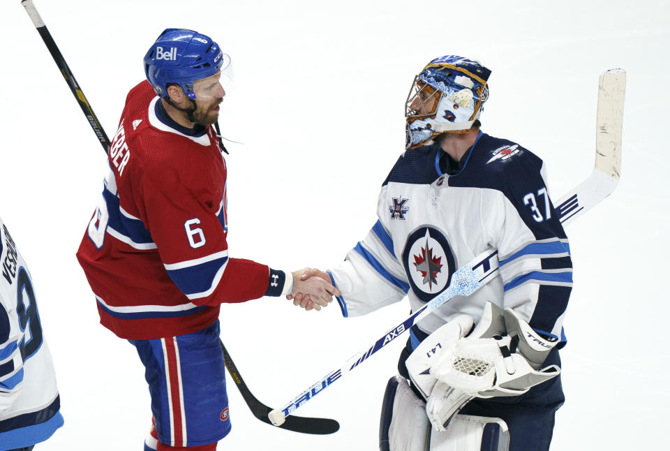 Montreal Canadiens captain Shea Weber (6) shakes hands with Winnipeg Jets goalie Connor Hellebuyck following overtime NHL Stanley Cup playoff hockey action in Montreal, Monday, June 7, 2021. (Paul Chiasson/The Canadian Press via AP)