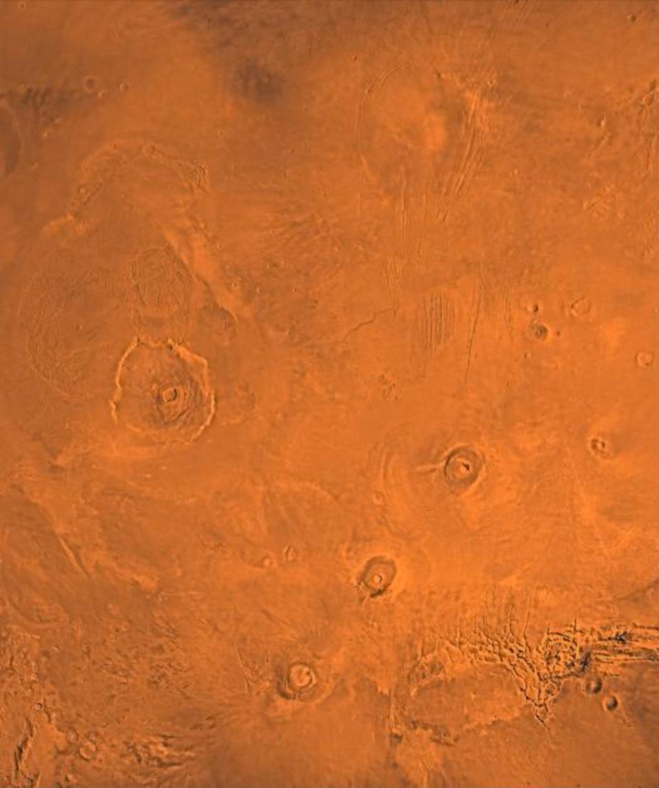 The Tharsis volcanic region of Mars, as seen by NASA's Viking mission. At left is the enormous Olympus Mons. The chain of volcanoes at lower right consists of, from bottom to top, Arsia, Pavonis and Ascraeus Mons. <cite>NASA/JPL/USGS</cite>