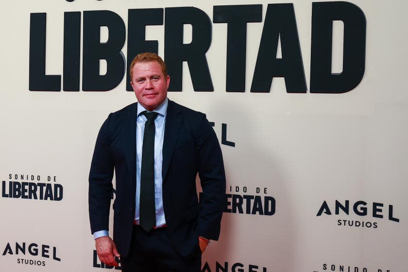 Activist Tim Ballard poses at a premiere with one hand in the pocket of a black suit, worn with a blue shirt and tie