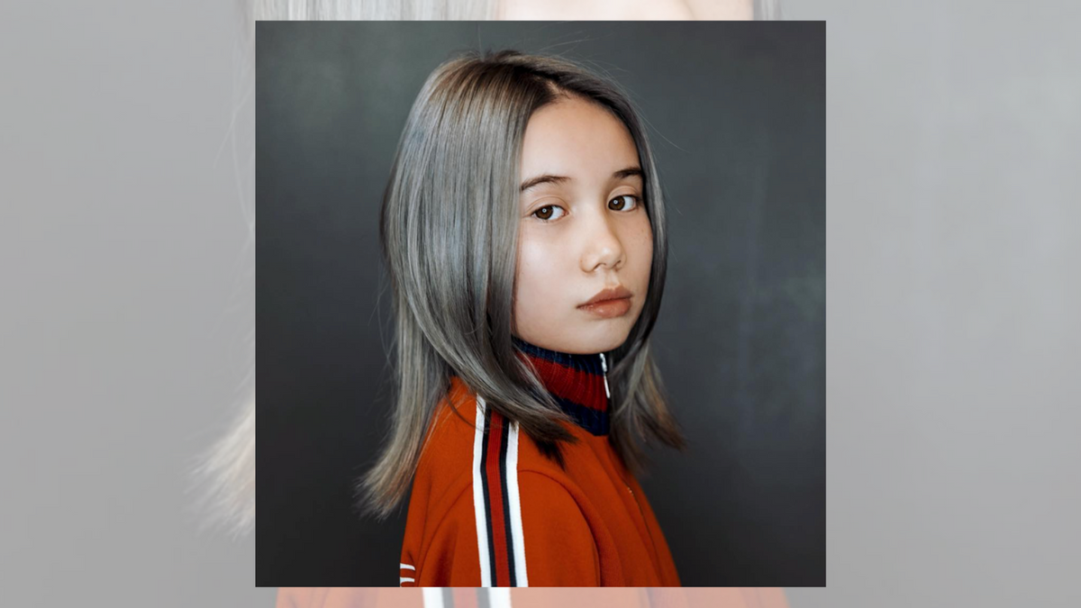 A white girl with silver hair in an orange jacket looks towards the camera. @liltay/Instagram