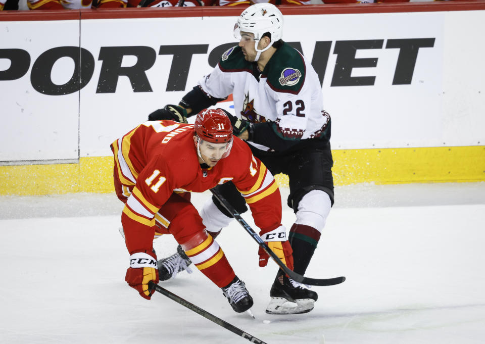 Arizona Coyotes forward Jack McBain (22) checks Calgary Flames forward Mikael Backlund (11) during the second period of an NHL hockey game, Tuesday, Jan. 16, 2024 in Calgary, Alberta. (Jeff McIntosh/The Canadian Press via AP)