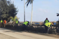 In this photo provided by Broadcom Broadcasting, people clear debris off the street in Nuku'alofa, Tonga, Thursday, Jan. 20, 2022, following Saturday's volcanic eruption near the Pacific archipelago. The first flight carrying fresh water and other aid to Tonga was finally able to leave Thursday after the Pacific nation's main airport runway was cleared of ash left by the eruption. (Marian Kupu/Broadcom Broadcasting via AP)