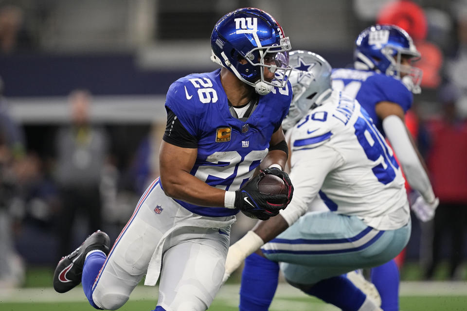 New York Giants running back Saquon Barkley (26) carries past Dallas Cowboys defensive end DeMarcus Lawrence (90) in the first half of an NFL football game, Sunday, Nov. 12, 2023, in Arlington, Texas. (AP Photo/Tony Gutierrez)