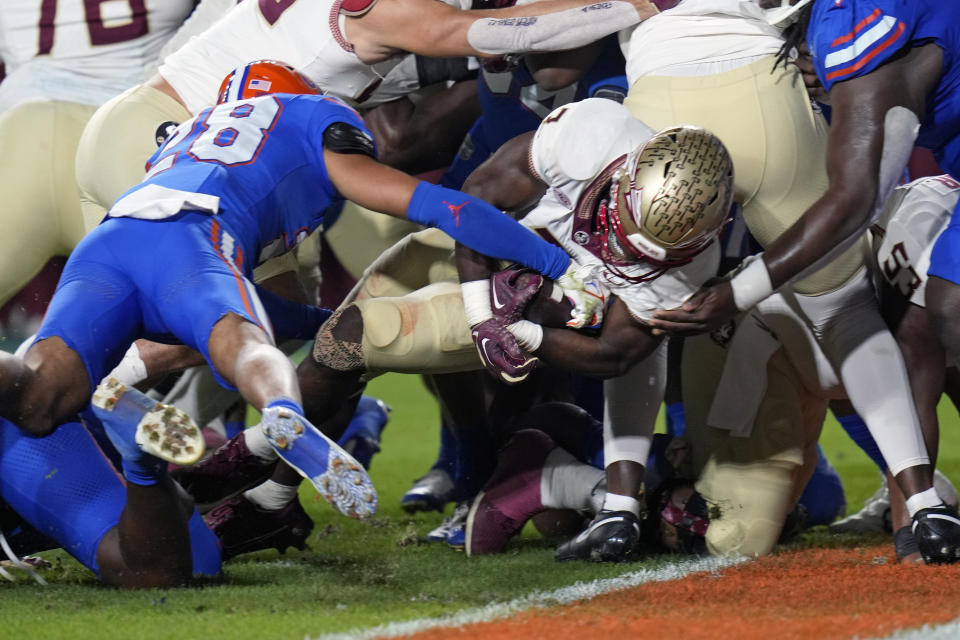 Florida State running back Trey Benson, center, pushes past the Florida defense for a 1-yard touchdown during the first half of an NCAA college football game Saturday, Nov. 25, 2023, in Gainesville, Fla. (AP Photo/John Raoux)