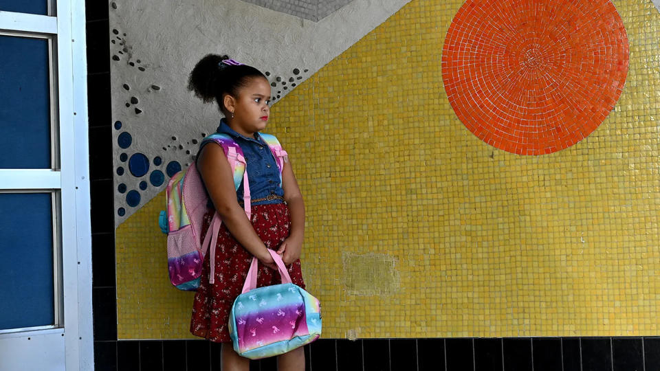 Second grader Valentina Oliveira was the first student to arrive for the first day of school last year at Memorial Elementary School in Milford. She waits patiently for the doors to open.