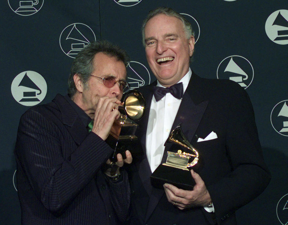 FILE - Herb Alpert, left, makes a trumpet of his Grammy award alongside Jerry Moss, as the two hold their Trustee Awards during the 39th Annual Grammy Awards in New York on Feb. 26, 1997. Moss, a music industry giant who co-founded A&M Records, died Wednesday at his home in Bel Air, Calif. He was 88. (AP Photo/Kathy Willens, File)