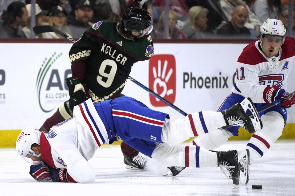 Arizona Coyotes right wing Clayton Keller (9) sends Montreal Canadiens defenseman Mike Matheson (8) to the ice as Canadiens right wing Brendan Gallagher (11) skates to the puck during the third period of an NHL hockey game Thursday, Nov. 2, 2023, in Tempe, Ariz. (AP Photo/Ross D. Franklin)