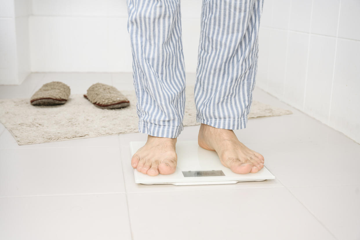 Man standing on weight scale in bathroom at home