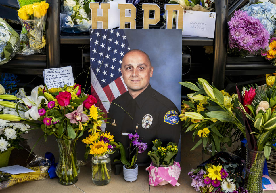 A photo of Huntington Beach police officer Nicholas Vella is displayed amongst flowers and notes as part of a memorial outside the Huntington Beach Police Department in Huntington Beach, Calif., Sunday, Feb. 20, 2022. Officer Vella, 44, a 14-year veteran of the Huntington Beach Police Department was killed Saturday in a helicopter crash in Newport Beach. (Leonard Ortiz/The Orange County Register via AP)