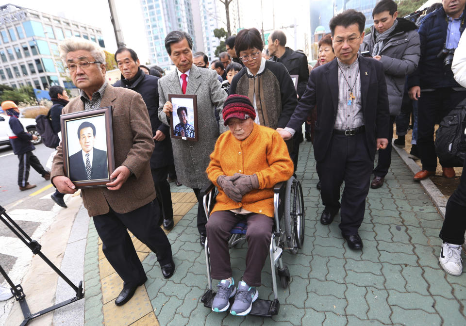 FILE - In this Nov. 29, 2018, file photo, Kim Sung-joo, bottom center, a victim of Japan's forced labor, arrives at the Supreme Court's in Seoul, South Korea. South Korea's top court ordered a Japanese company to compensate 10 Koreans for forced labor during Tokyo's 1910-45 colonial rule of the Korean Peninsula. The modern legacy of a dark chapter in Japan’s history, when hundreds of thousands of people were brought from the Korean Peninsula and other Asian nations to work in logging, in mines, on farms and in factories as forced labor, lives on in the companies that came to dominate the Japanese economy after World War II. Many of those companies are still facing demands for compensation that they say were settled by treaty decades ago. (AP Photo/Ahn Young-joon, File)