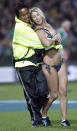 A woman is taken off the field by a security guard near the end of an international rugby union match between the All Blacks and Ireland in Hamilton, June 10, 2006. REUTERS/Anthony Phelps