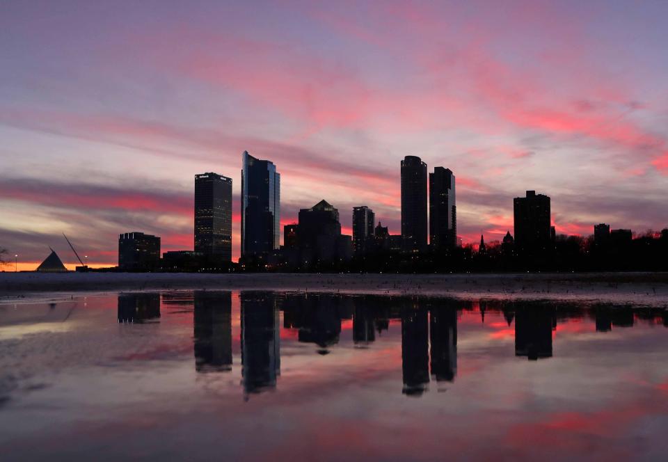The sun sets behind the Milwaukee skyline reflected in a puddle of melting snow at Veterans Park in Milwaukee on Sunday, Feb. 2, 2020.