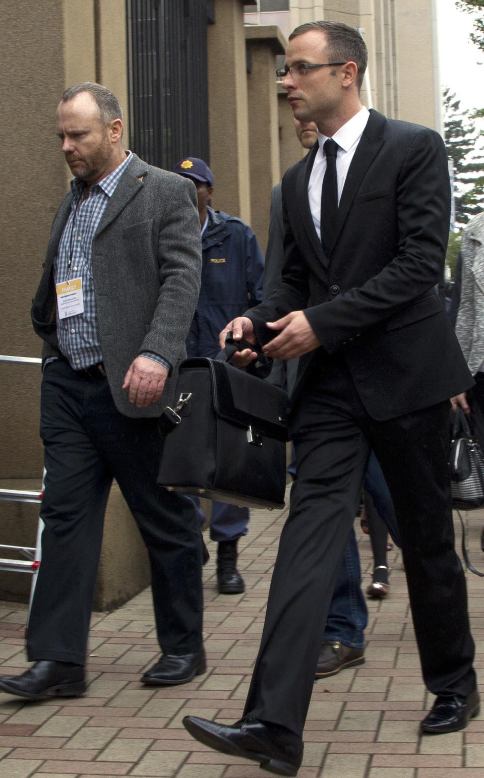 Oscar Pistorius, right, accompanied by a relative arrives at the high court in Pretoria, South Africa, Friday, March 14, 2014. Pistorius is charged with murder for the shooting death of his girlfriend, Reeva Steenkamp, on Valentines Day in 2013. (AP Photo/Themba Hadebe)