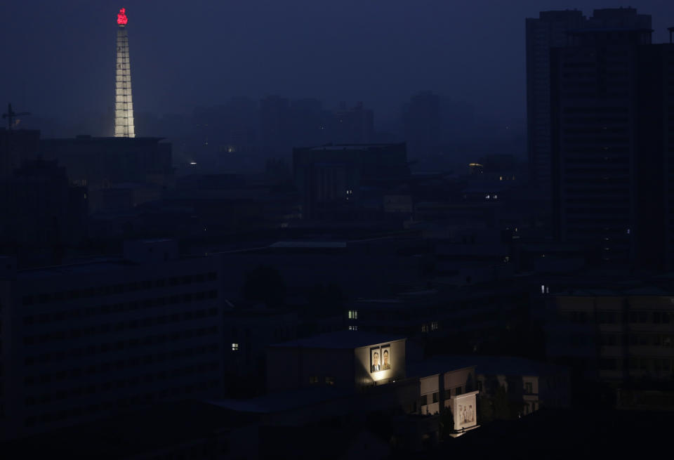 FILE - In this June 19, 2018, file photo, portraits of the late North Korean leaders Kim Il Sung and Kim Jong Il are illuminated on a building as the Tower of Juche Idea is seen in the background at dawn in Pyongyang, North Korea. The word Juche is splashed across countless propaganda signs in North Korea and featured in hundreds of state media reports, and while it’s technically a political ideology, it can seem more like a religion because of its difficulty for many outsiders to grasp and ability to inspire devotion among North Koreans. (AP Photo/Dita Alangkara, File)