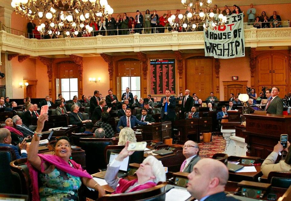 Some members of the Ohio House applaud following their vote while others photograph protestors who unfurled banners reading "This is not a House of Worship" and "This is not a Doctor's office" following a vote on the Heartbeat Bill at the Ohio Statehouse in Columbus, Ohio on Wednesday, April 10, 2019. The House members voted in the controversial "Heartbeat Bill" that bans abortion at the first sounds of a fetal heartbeat, which is around 6 weeks after conception. Many protestors shouted in the hallway outside of the meeting where House members decided to pass the bill. (Brooke LaValley/The Columbus Dispatch via AP)