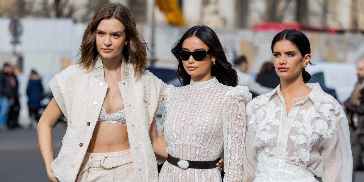 paris, france march 06 josephine skriver wears sleeveless jacket, bra, pants kelsey merrit wears white laced belted dress, black boots sara sampaio wears white embroidered blouse, skirt, pointed heels outside zimmermann during paris fashion week womenswear fall winter 2023 2024 day eight on march 06, 2023 in paris, france photo by christian vieriggetty images