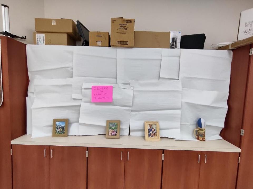 Bookcases filled with books but covered up by chart paper and a sign that says "Closed by order of the governor."