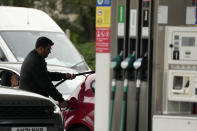 A man puts fuel in his car as drivers queue at a petrol station in London, Tuesday, Sept. 28, 2021. Long lines of vehicles have formed at many gas stations around Britain since Friday, causing spillover traffic jams on busy roads. (AP Photo/Frank Augstein)