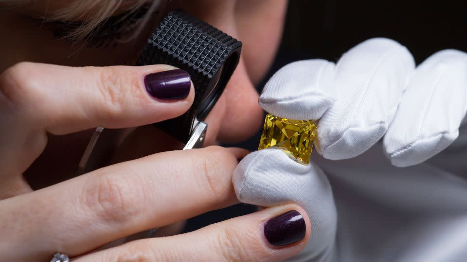 An employee inspects a deep yellow asscher cut diamond, weighing 20,69 carats — the largest yellow diamond mined in Russia in 2017, at an exhibition of Alrosa collection of large colored diamonds in Moscow on February 13, 2019. - Andrey Rudakov/Bloomberg/Getty Images