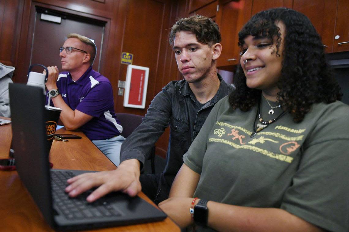 Fresno High student Chris Garrett, 17, center, helps Kenissa Austin,18, right, check her CalKIDS college savings account with vice principal John Kaup in the background Wednesday, Aug. 17, 2022 in Fresno.