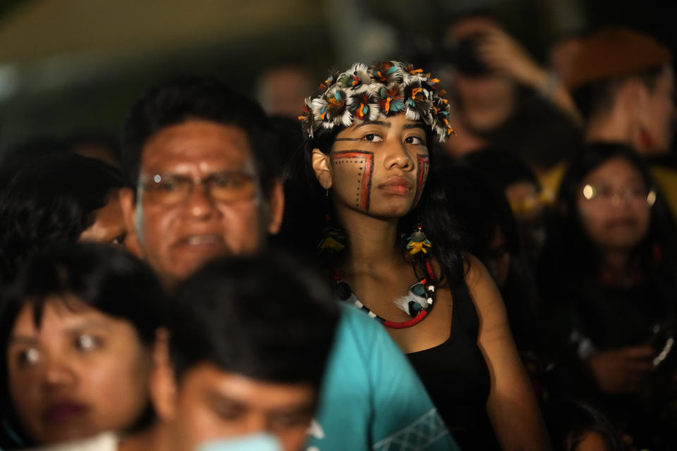 Attendees record as Indigenous models wear creations from Indigenous designers during a fashion event, as part of the Third March of Indigenous Women, to claim women's rights and the demarcation of Indigenous lands, in Brasilia, Brazil, Tuesday, Sept. 12, 2023. (AP Photo/Eraldo Peres)