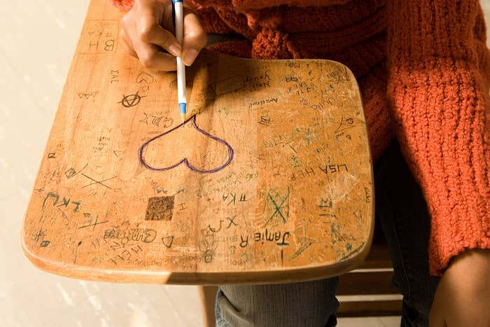 student drawing a heart on a desk