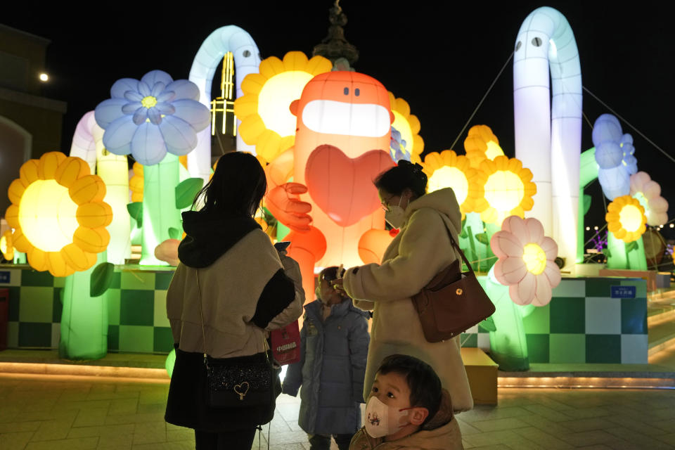 A child wearing a mask stands near light decorations at a mall in Beijing, Friday, Dec. 30, 2022. China is on a bumpy road back to normal life as schools, shopping malls and restaurants fill up again following the abrupt end of some of the world's most severe restrictions even as hospitals are swamped with feverish, wheezing COVID-19 patients. (AP Photo/Ng Han Guan)