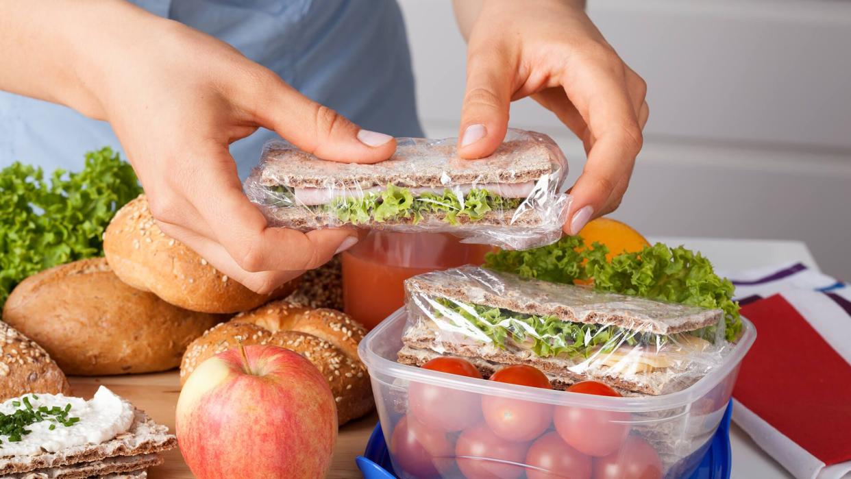 Woman preparing takeaway meal for her child - Image.