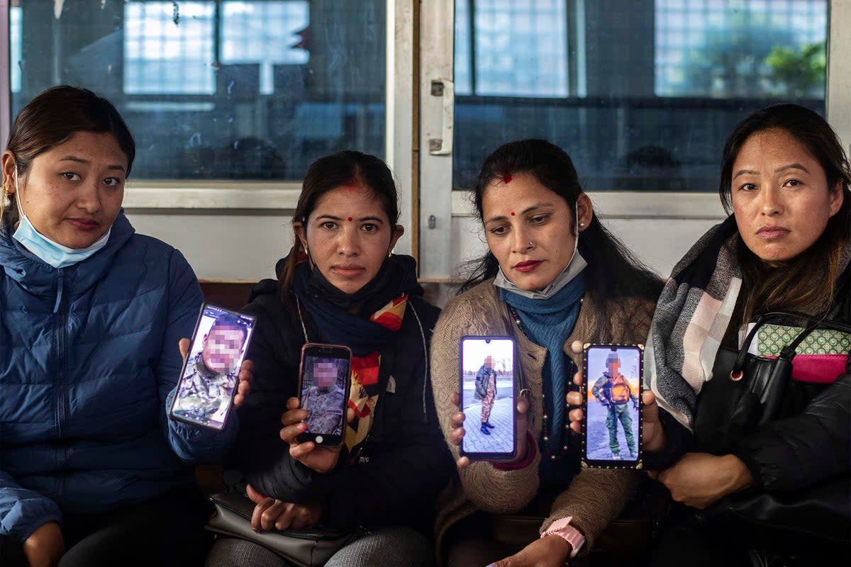 Nepalese wives showing images of their husbands in Russian army uniforms (images blurred upon the wives’ request) in Kathmandu, Nepal (EPA)