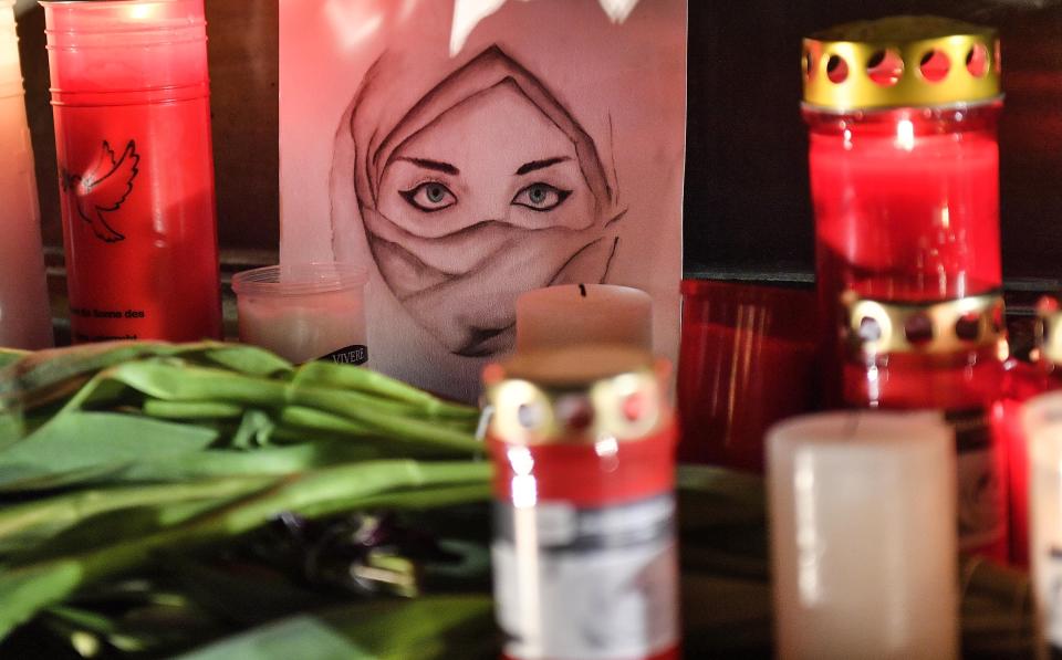 FILE - In this Feb. 20, 2020, file photo, a picture of a woman is seen between candles and flowers at a monument on the market place during mourning for the victims of a shooting in Hanau, Germany. The rampage this week in Germany in which a gunman killed nine people with foreign backgrounds was the country's third deadly far-right attack in a matter of months. German leaders openly acknowledge there is a problem, but so far, identifying a solution has been elusive. (AP Photo/Martin Meissner, File)