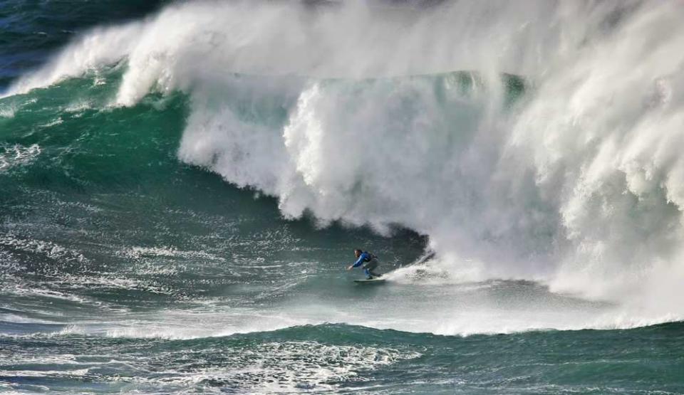 A daredevil surfer takes on a 60ft wall of water called The Cribbar, but nicknamed 'The Widow Maker' in Newquay as storms whipped up the surf on the south coast. (SWNS)