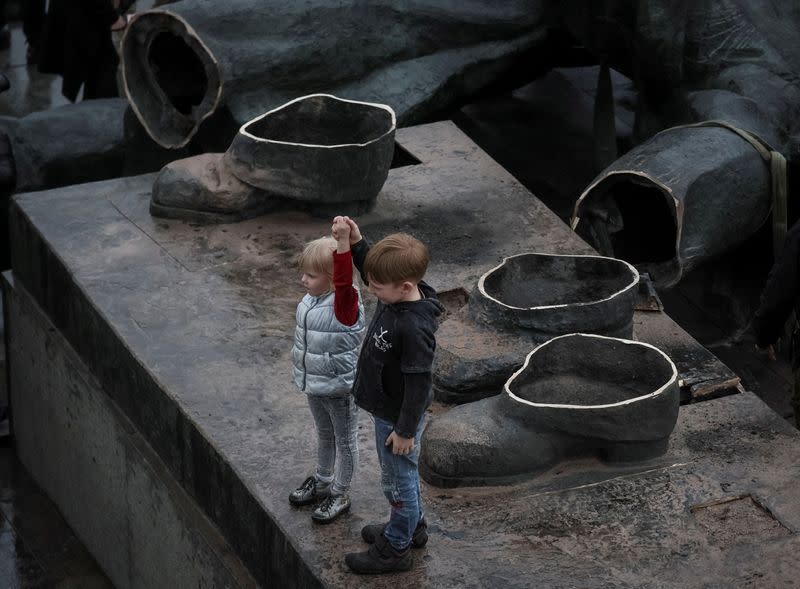 Children depict a Soviet monument to a friendship between Ukrainian and Russian nations after its demolition in central Kyiv