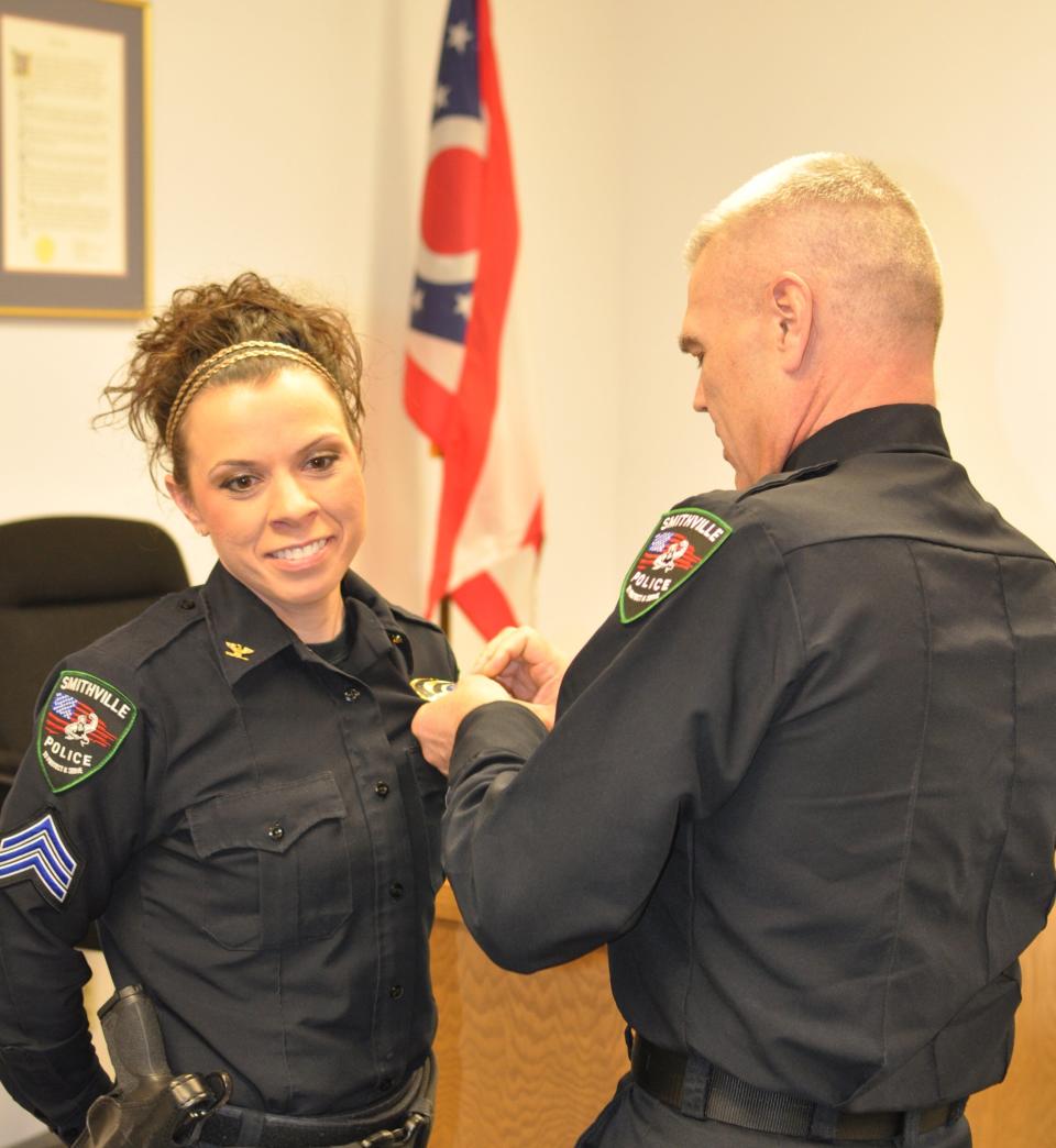 Former Smithville Police Chief Howard Funk pins the chief's badge on his successor Jen Barnett.