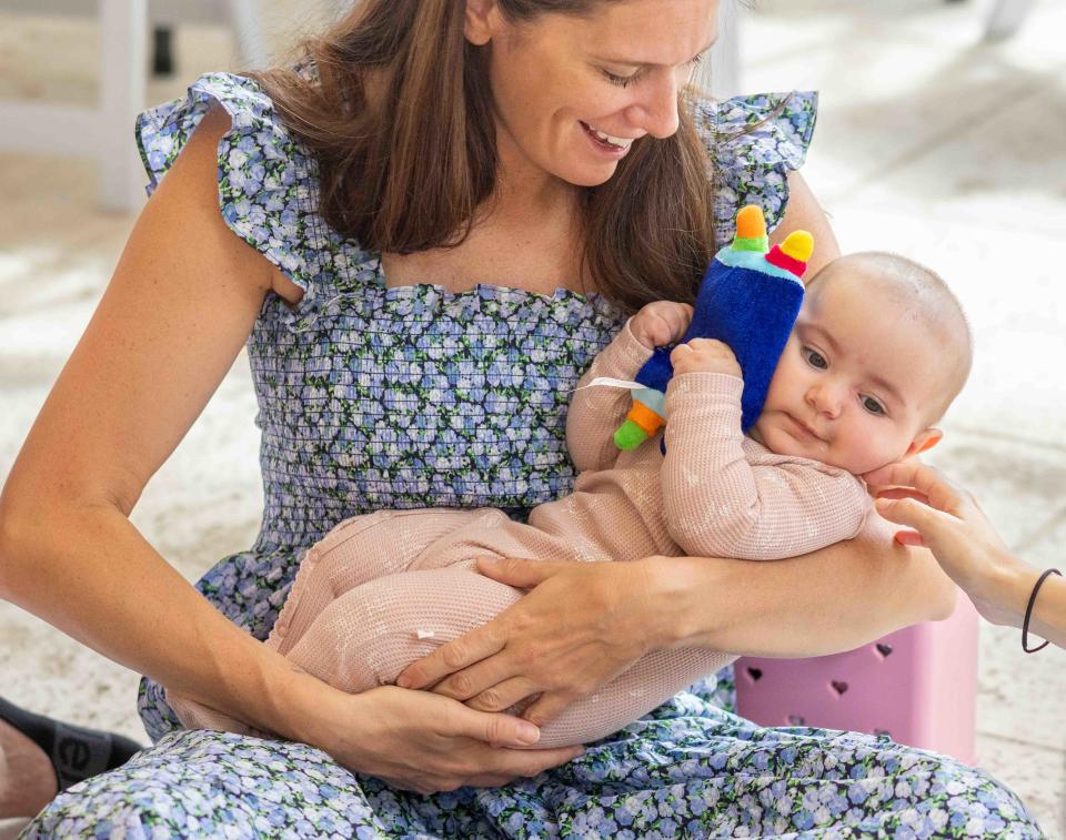 Natasha Mirakhor holds Riva Krasnianski, 5 months, who is cuddling a stuffed Torah during the Mommy & Me class.