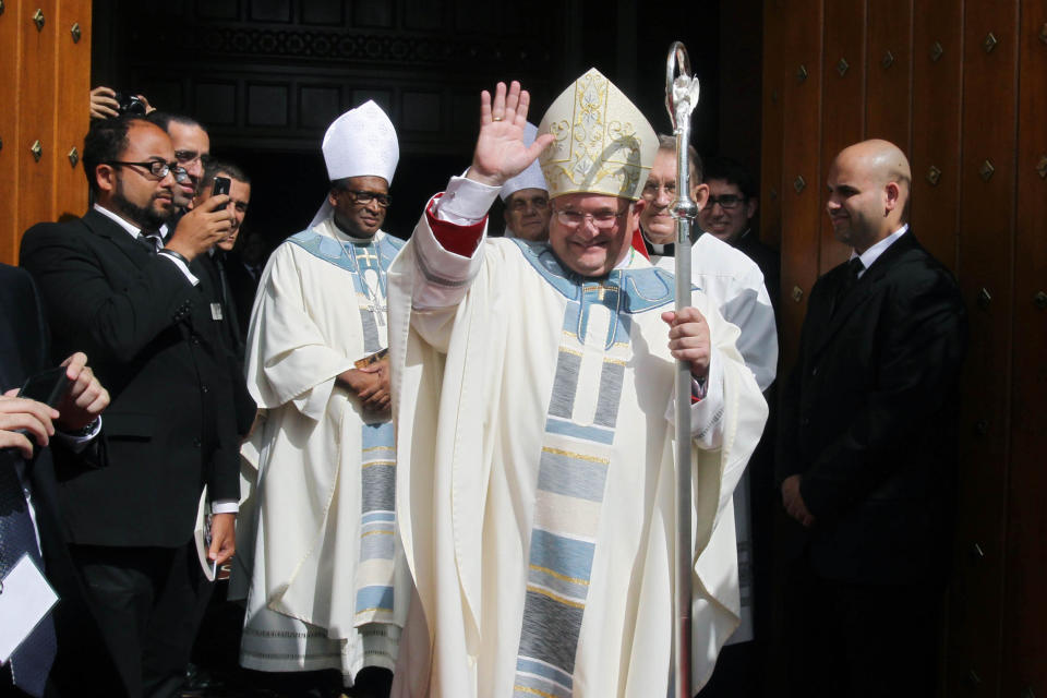 FILE - In this March 19, 2014, file photo, then-Auxiliary bishop-elect Peter Baldacchino, front, waves after his Ordination Mass at St. Mary Cathedral in North Miami, Fla. Baldacchino, who is now a bishop in Las Cruces, N.M. announced Wednesday, April, 15, 2020, that the Las Cruces Diocese would "reopen" churches and lift the ban on public celebrations of Mass, a move believed to be a first by a diocese in the U.S. amid the coronavirus pandemic. (Roberto Koltun/El Nuevo Herald via AP, File)