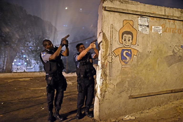 Rio de Janeiro's state military policemen aim their guns during a violent protest in a favela next to Copacabana, Rio de Janeiro on April 22, 2014