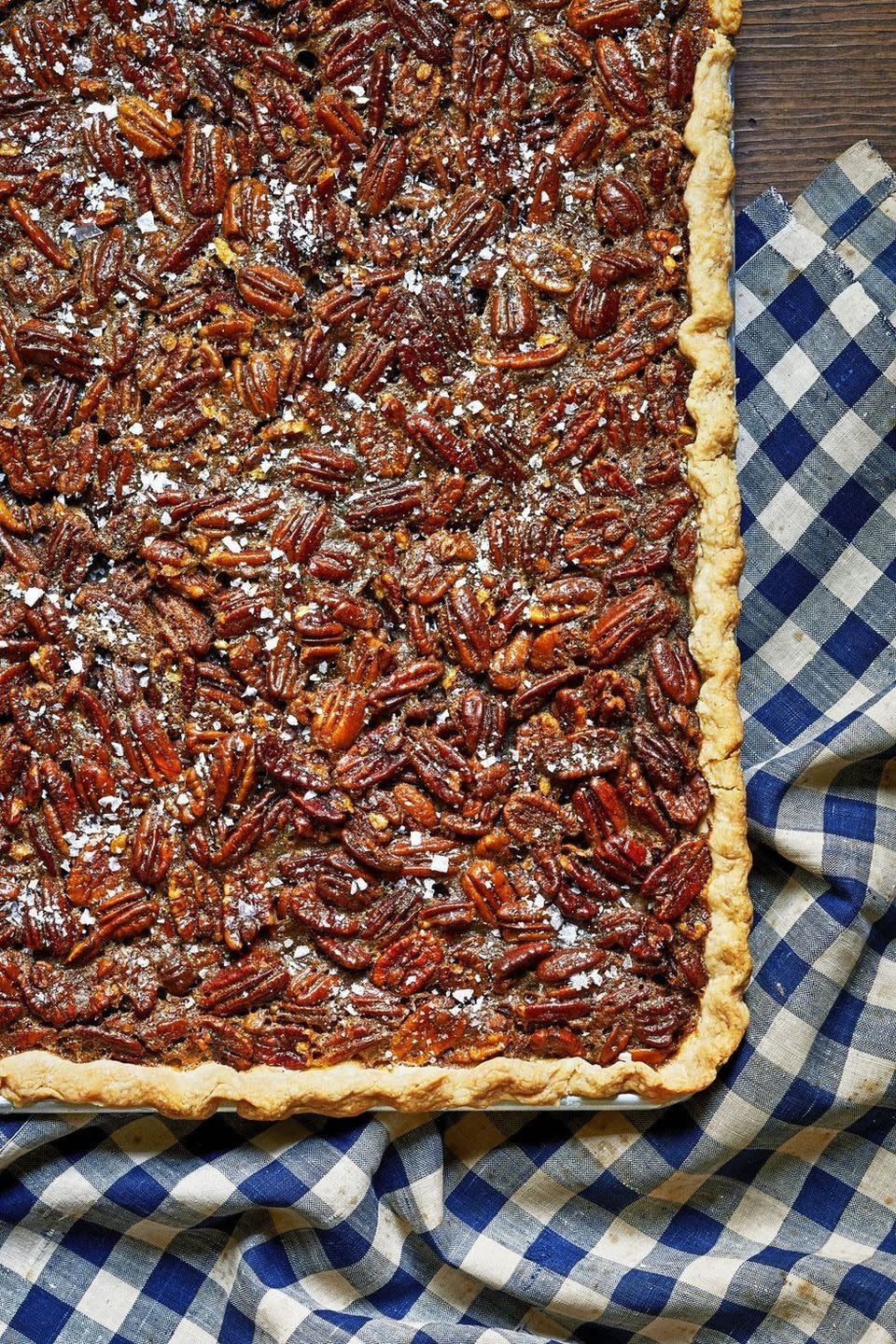 nancy fullers pecan slab pie in a rectangle pan on a navy blue gingham kitchen towel
