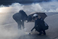 Protester use a plate to cover a tear gas canister fired by riot police as they face off near the Legislative Council building and the Central Government building in Hong Kong, Monday, Aug. 5, 2019. Droves of protesters filled public parks and squares in several Hong Kong districts on Monday in a general strike staged on a weekday to draw more attention to their demands. (AP Photo/Vincent Thian)