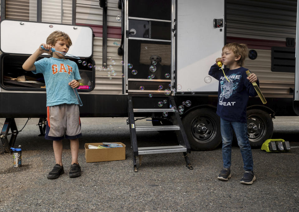 Twins Myles Muir, 7, and Matthew Muir, 7, from left, blow bubbles at the the Green Valley Community Church evacuation shelter on Thursday, Aug. 19, 2021, in Placerville, Calif., after their family fled the Caldor Fire. (AP Photo/Ethan Swope)