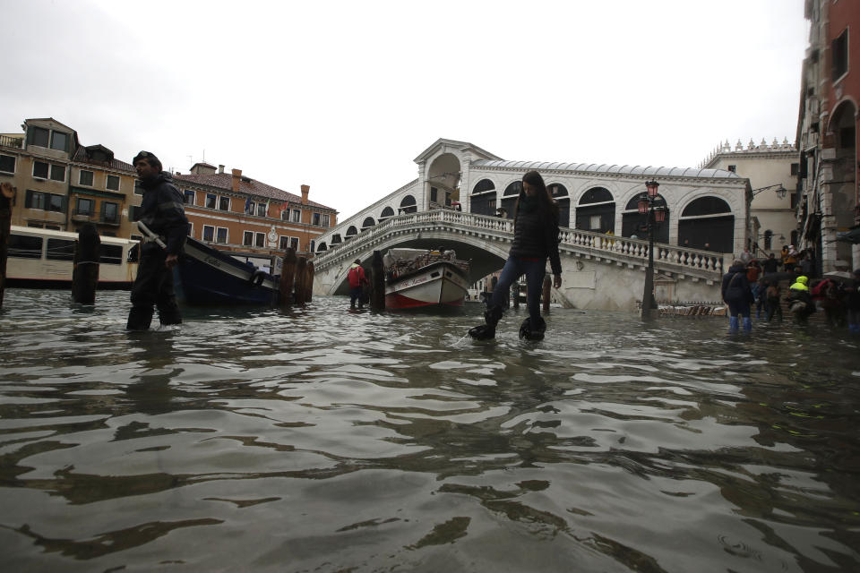 People walk in front of the Rialto bridge as water levels rise (AP)