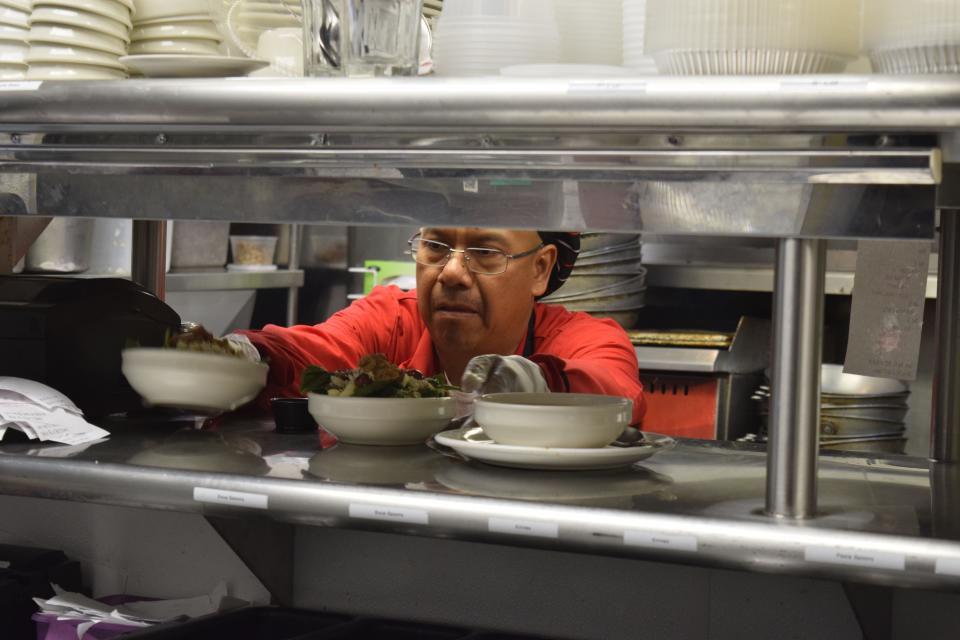 Willie Solis, a cook at Martinelli's Little Italy, places food on the kitchen line for a server to pick up during a busy lunch rush. Solis was one of the first employees hired at the restaurant when it opened 21 years ago.