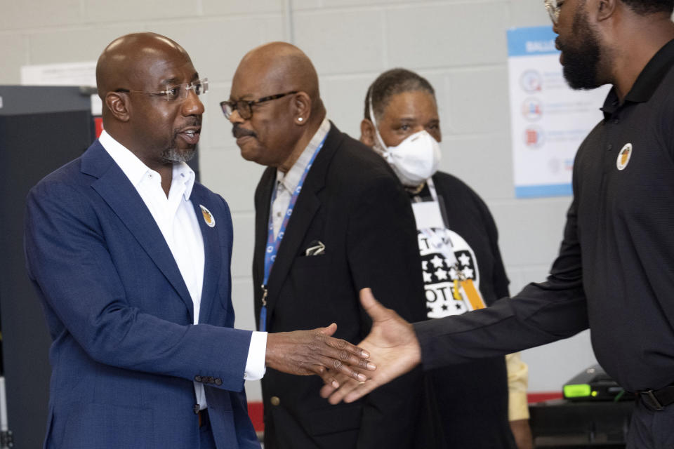 Sen. Raphael Warnock, D-Ga., shakes a supporter's hand after voting on the first day of early voting in Atlanta on Monday, Oct. 17, 2022. (AP Photo/Ben Gray)